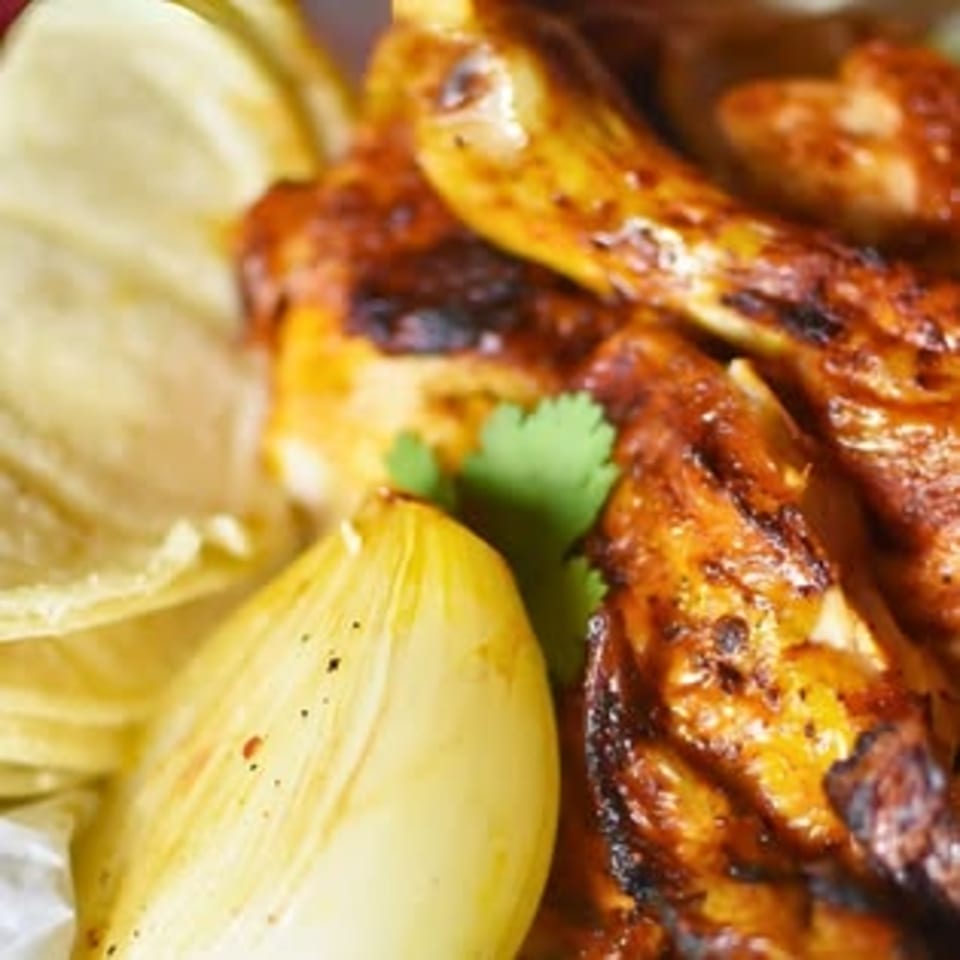 Close-up of Rey del Pollo's grilled chicken with cilantro, onions, and tortilla chips.