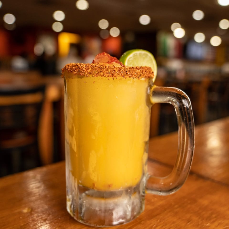 A Rey del Pollo mango margarita with chili-lime rim, garnished with lime and strawberry.