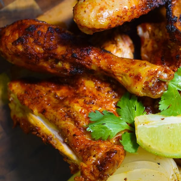 Close-up of Rey del Pollo's Mexican grilled chicken with cilantro, lime, and onions.